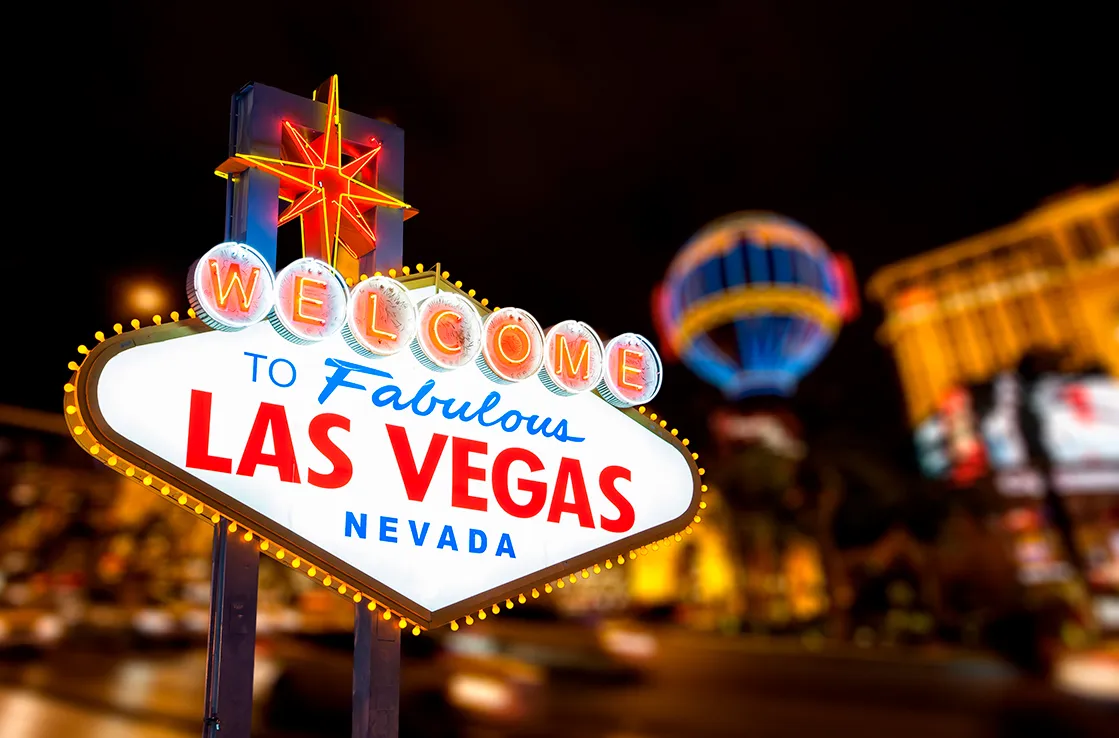 Näkymä Welcome to Fabolous Las Vegas Nevada -valokylttiin pimeään vuorokauden aikaan, taustalla Las Vegasin Paris Balloon